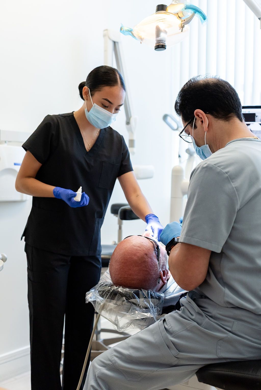 Dentist and patient in a clinic, with a dental procedure in progress and bright overhead light.