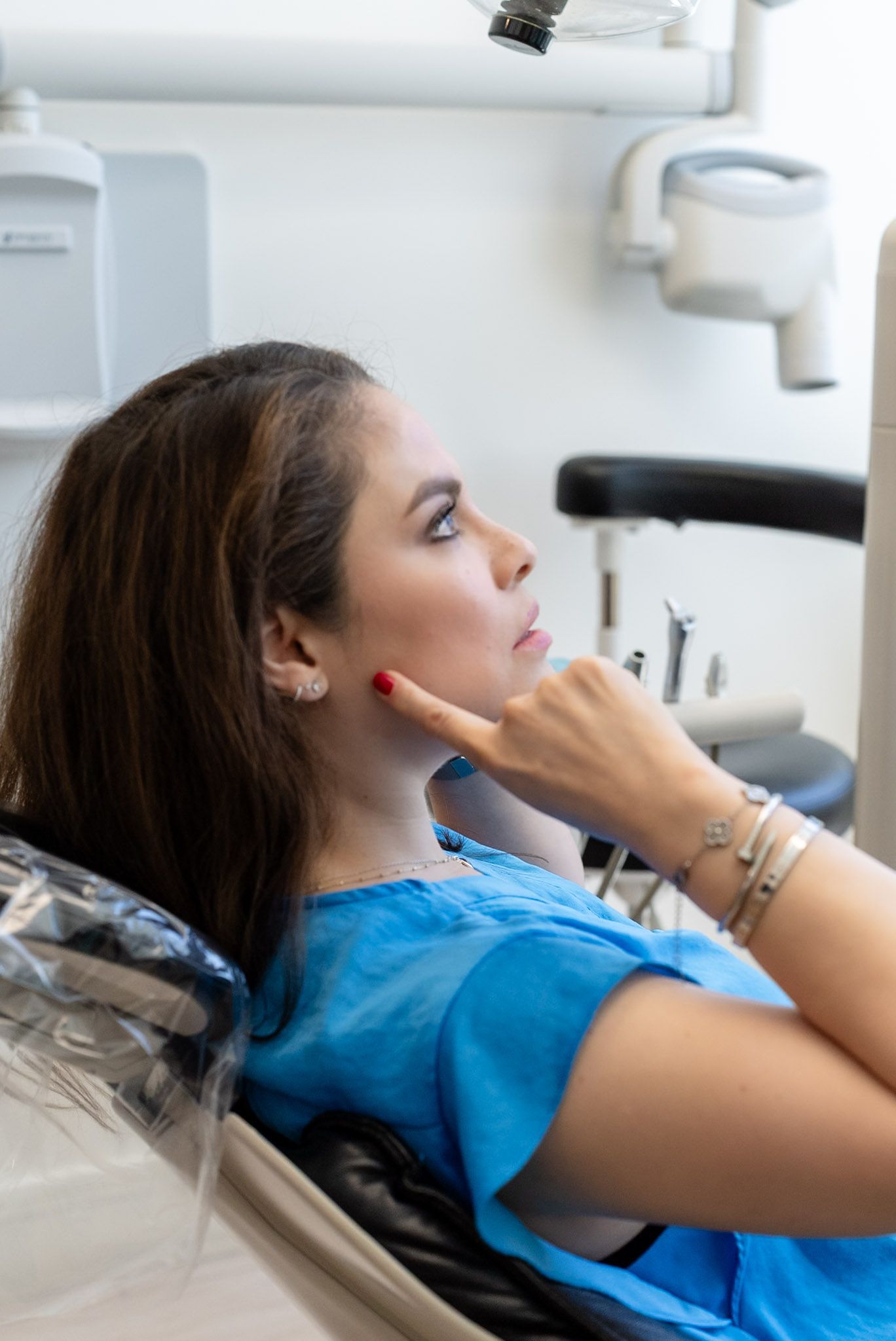 Patient touching her jaw while describing tooth pain to the dentist