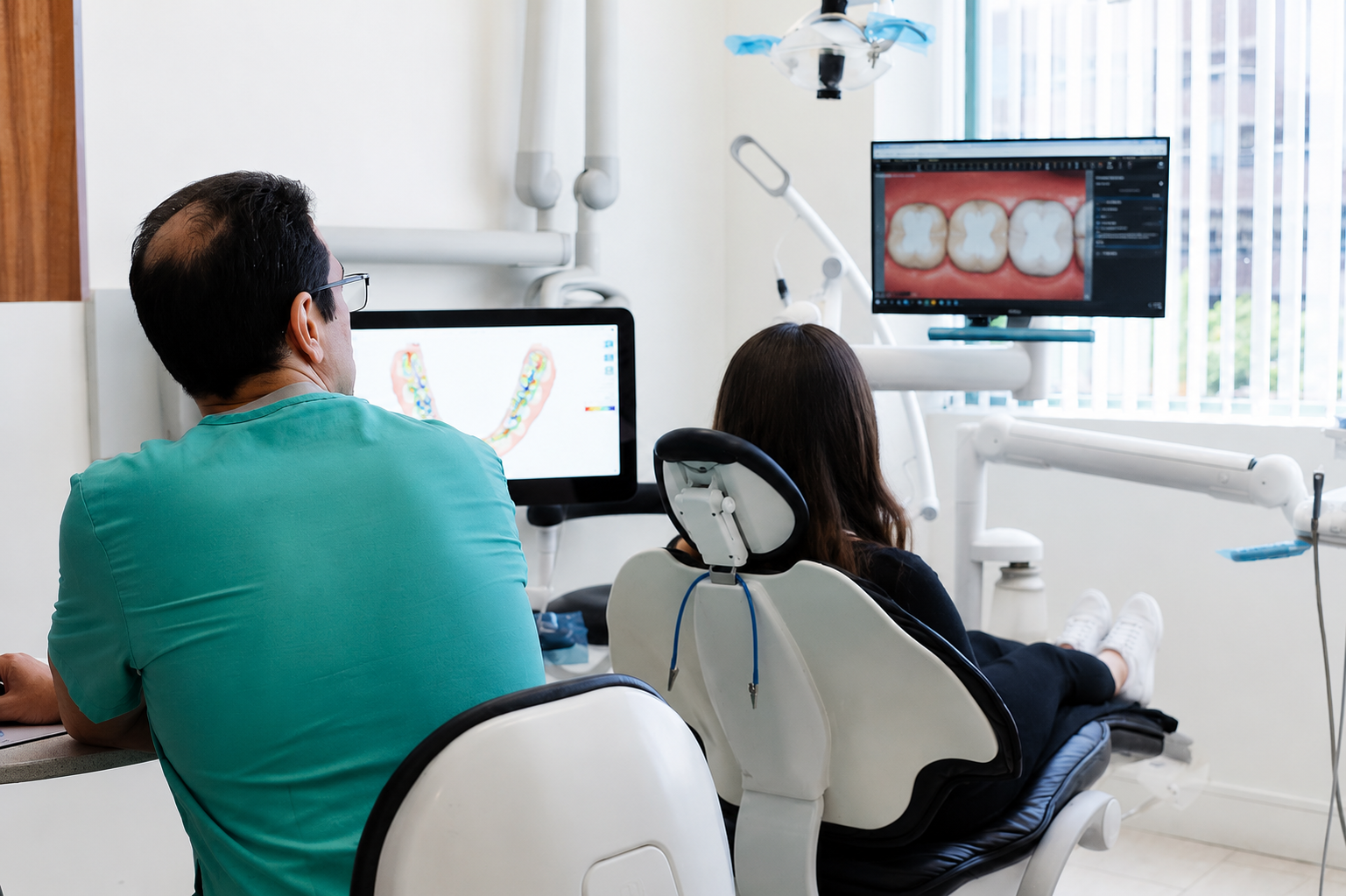 Two people seated in a dental clinic, viewing X-rays on a monitor during a consultation