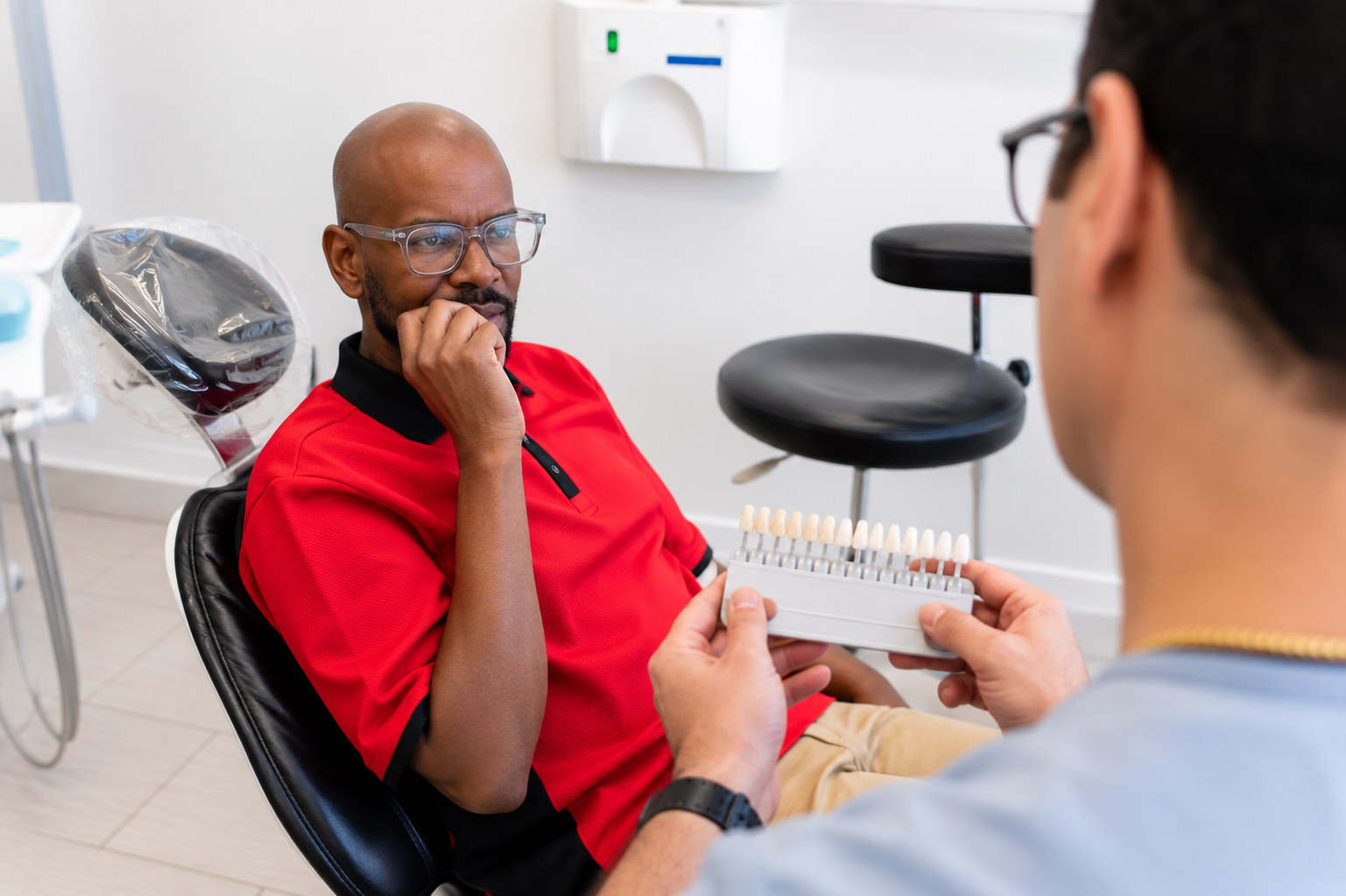 Dental patient in red shirt talking with a dentist in a clinic exam room