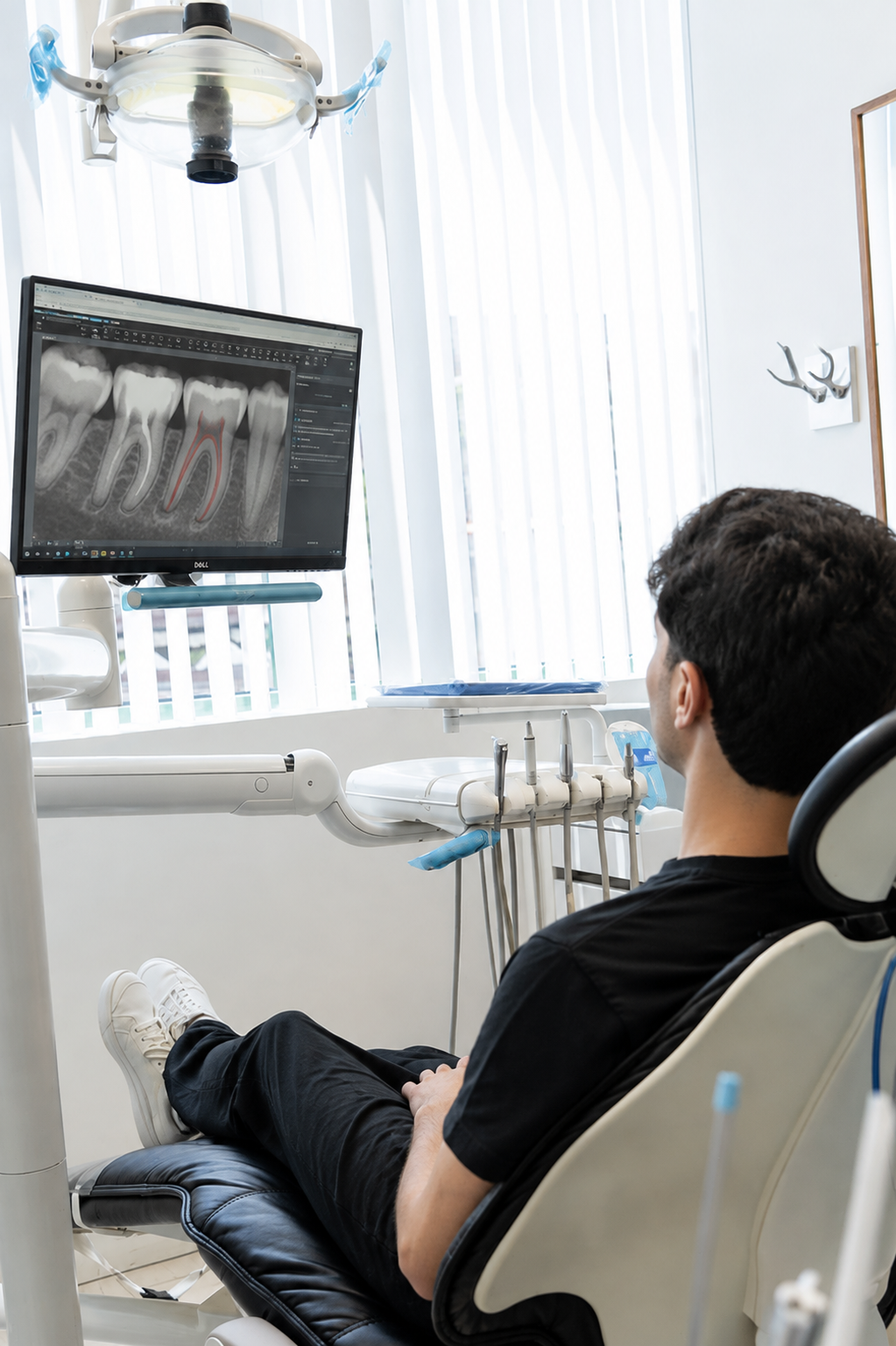 Dentist examining X-rays on a monitor while a patient reclines in a dental chair