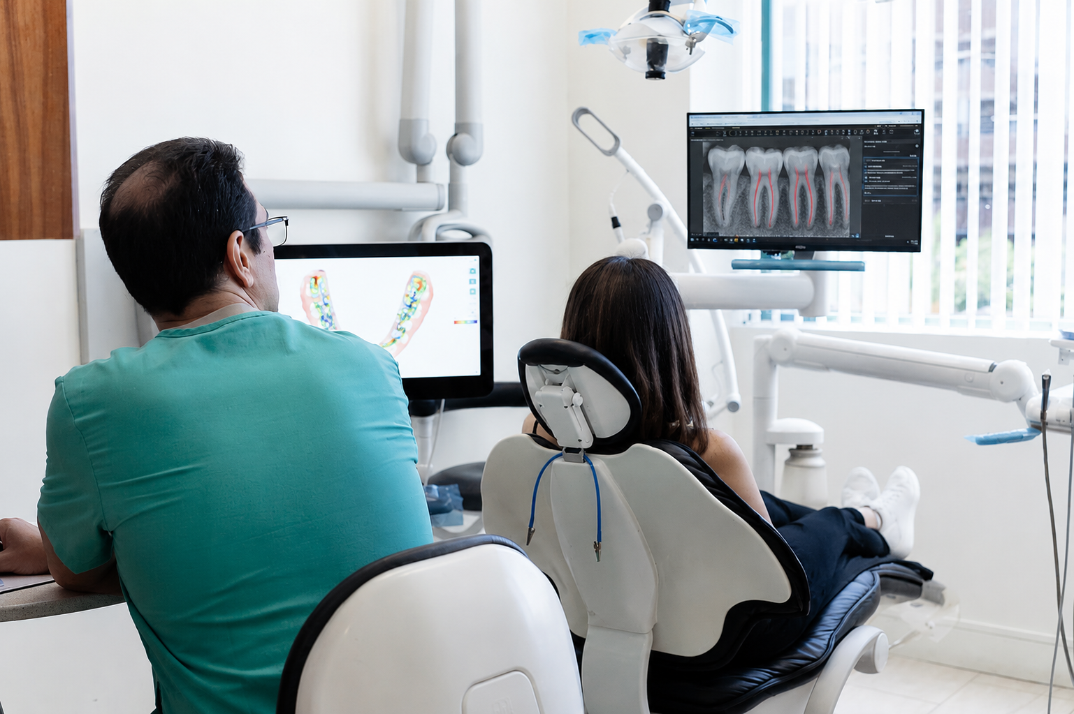 Dental clinic consultation with two people viewing X-rays on computer monitors