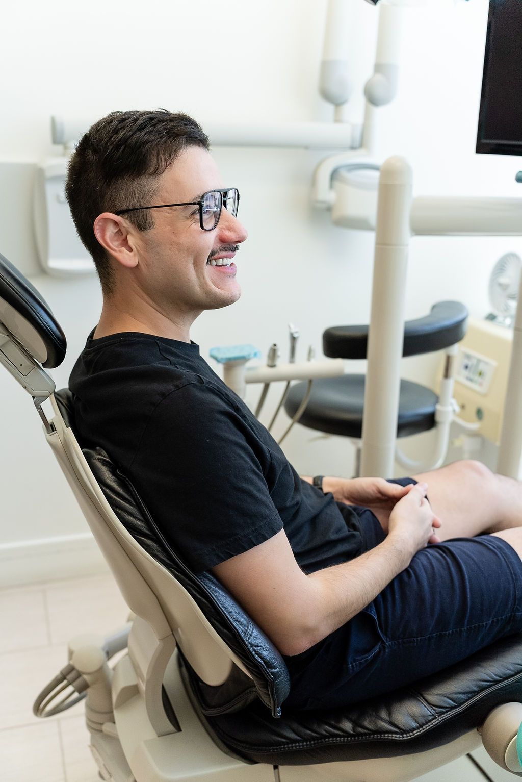 Man smiling while reclining in a dental chair during a checkup