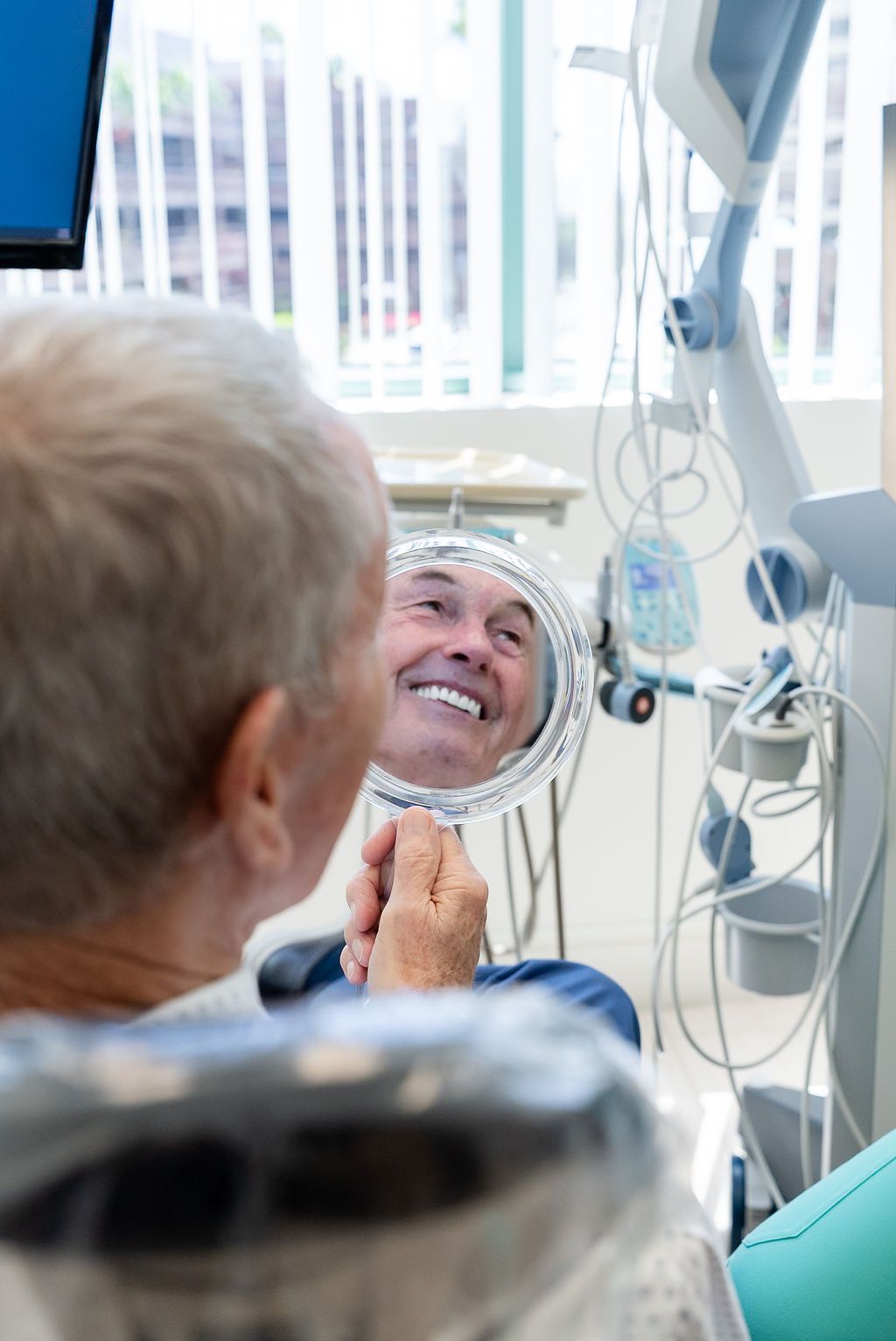 Hospital patient smiling in a mirror as another person adjusts something nearby