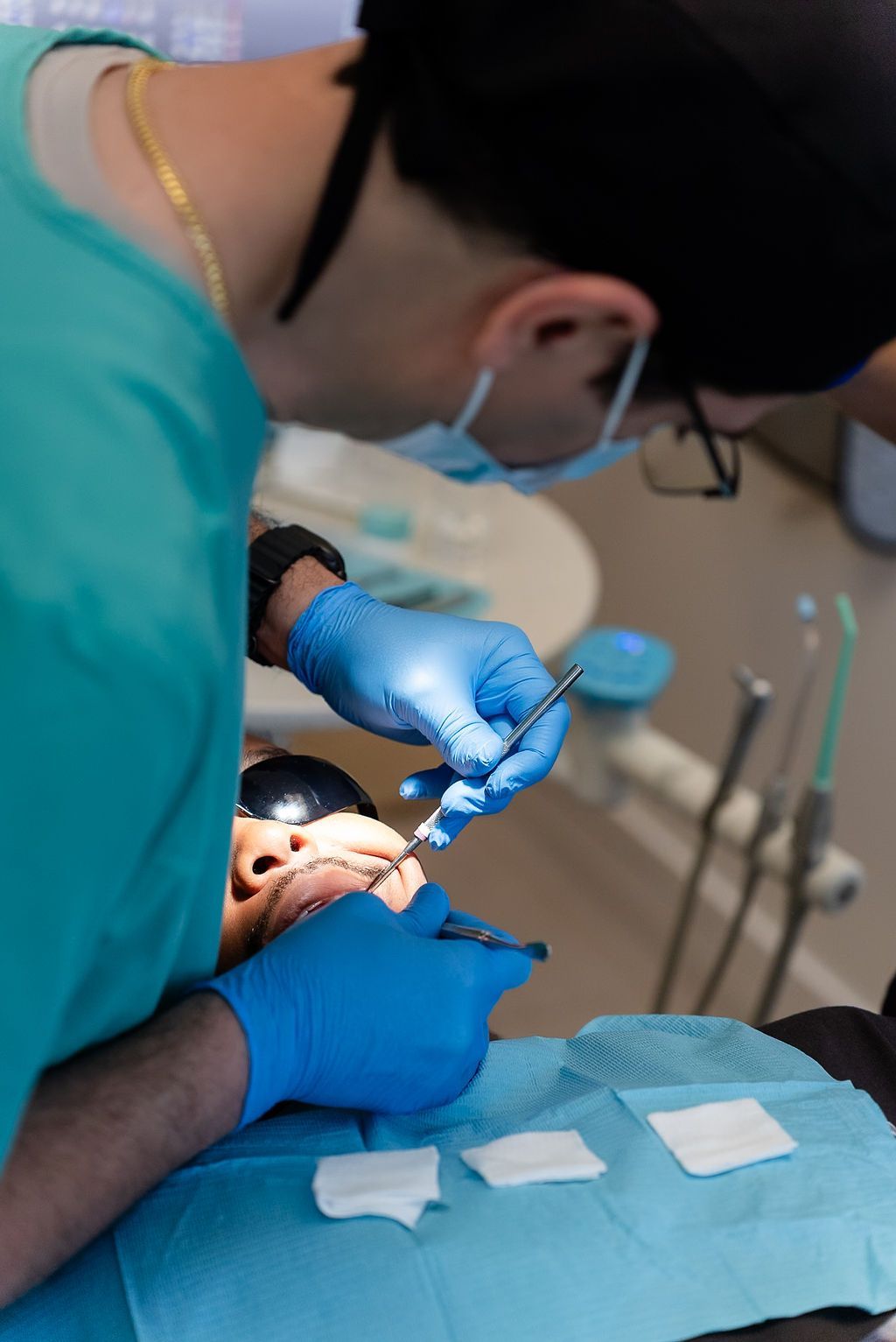 Dentist in blue gloves treating a patient’s mouth in a dental clinic
