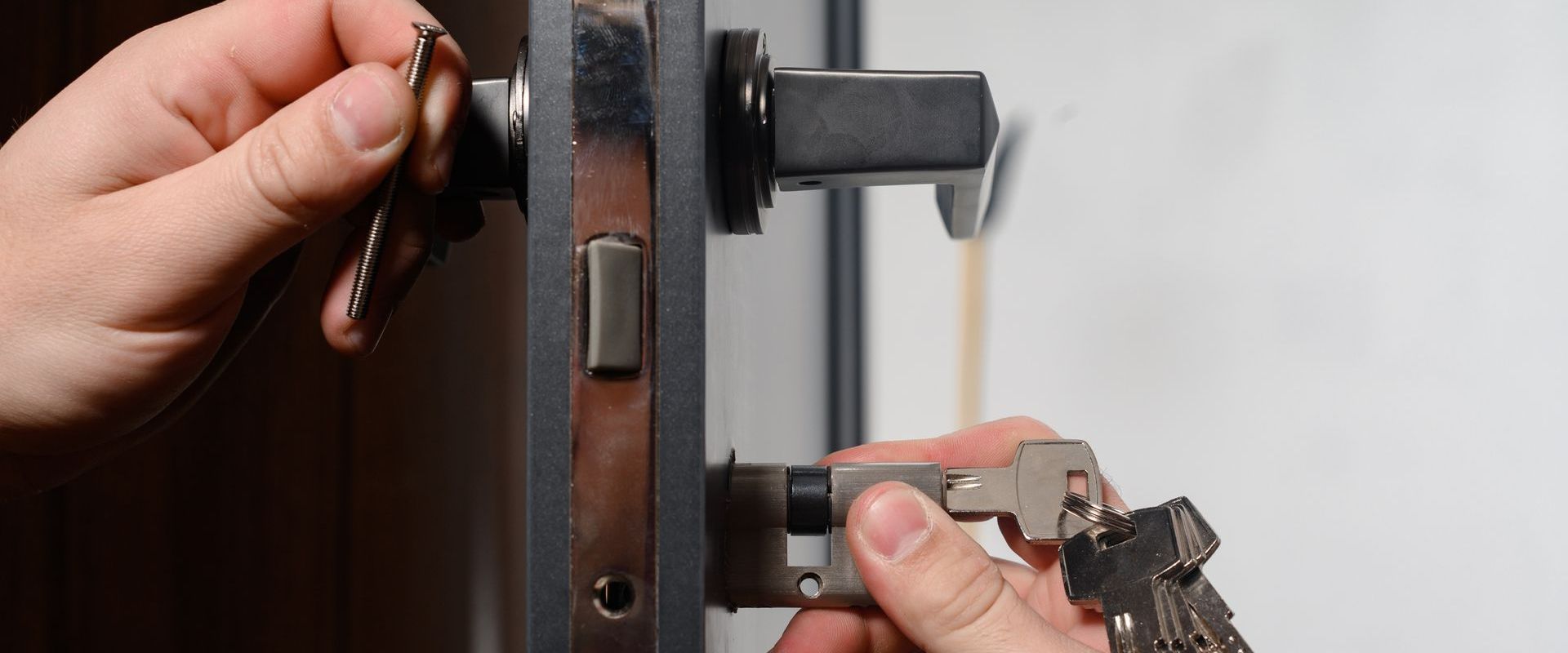 A person is fixing a door lock with a key.