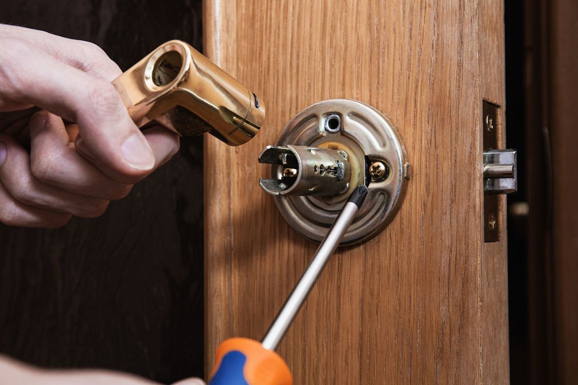 A person is fixing a door lock with a screwdriver.