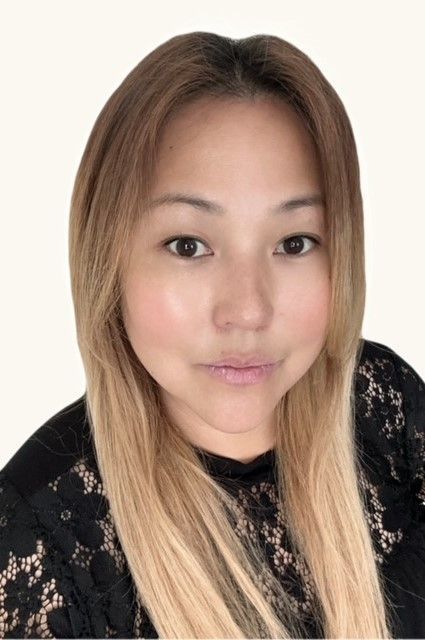 A person with shoulder-length, light brown hair wearing a black lace-patterned top against a plain white background.