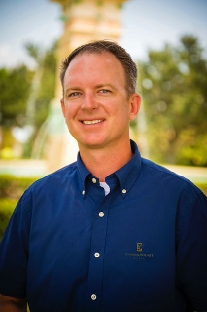 A man in a blue polo shirt is leaning against a wall.