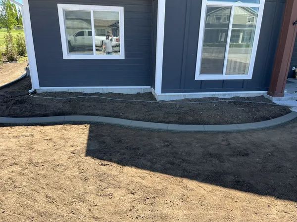 New home's front yard with fresh dirt and a curved concrete border under construction