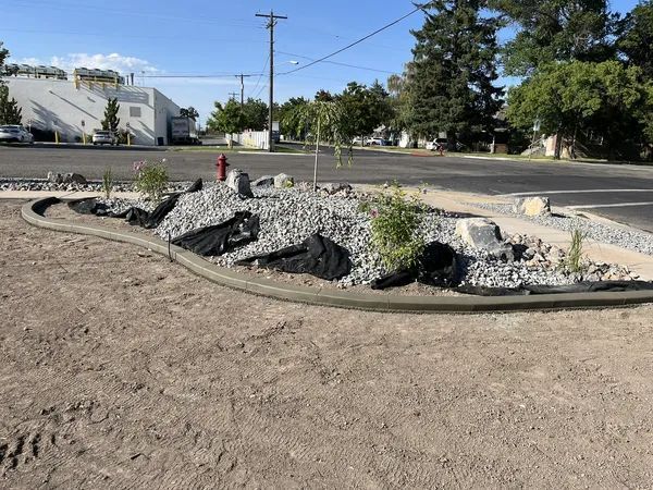 Rocky landscaped median with a red fire hydrant beside a road under a blue sky