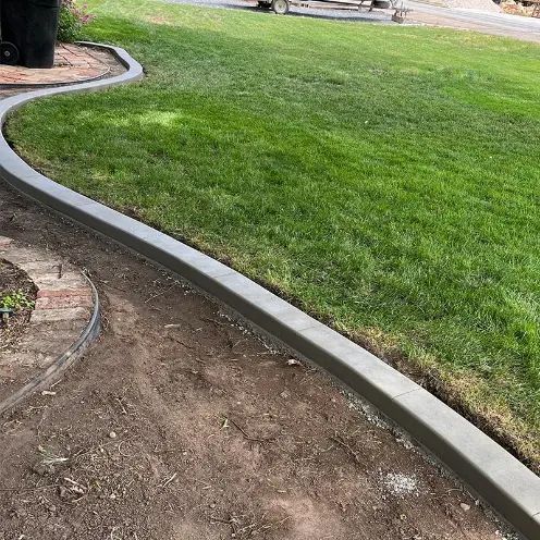 Curved concrete lawn edging separating green grass from bare dirt in a yard