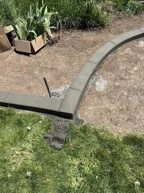 Garden border edging with a corner seam beside grass and a planter box