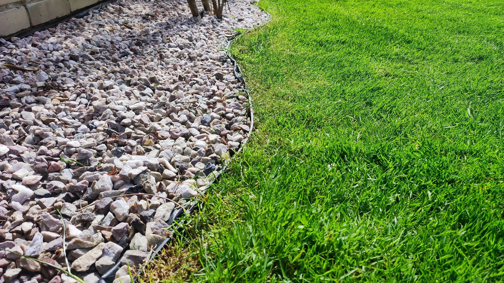 Curved border between white gravel and bright green lawn in a landscaped yard