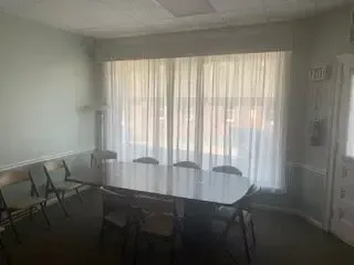 Conference room with table, chairs, and large curtained window