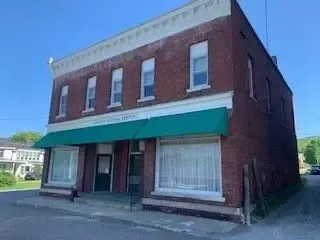 Brick storefront building with green awning on a quiet street corner