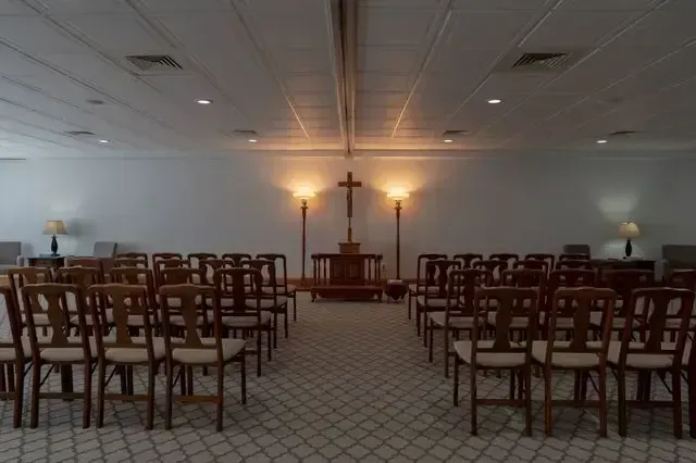 Empty chapel with rows of wooden chairs facing a lit altar at the front.