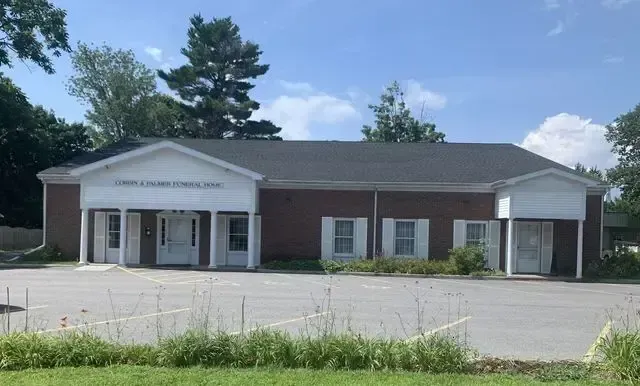 One-story brick office building with white columns and a parking lot in front