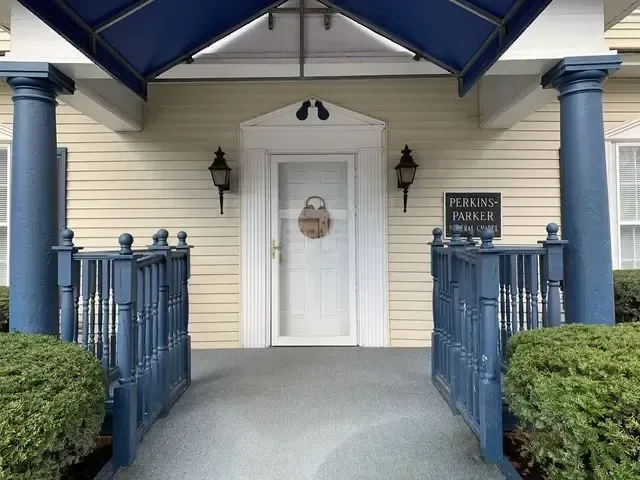 Front entrance with blue railings, white door, and covered porch at a building.