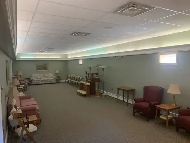 Empty waiting room with rows of chairs, side tables, and a couch under soft ceiling lights.