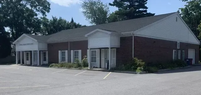 Single-story brick and beige commercial building with a parking lot in front