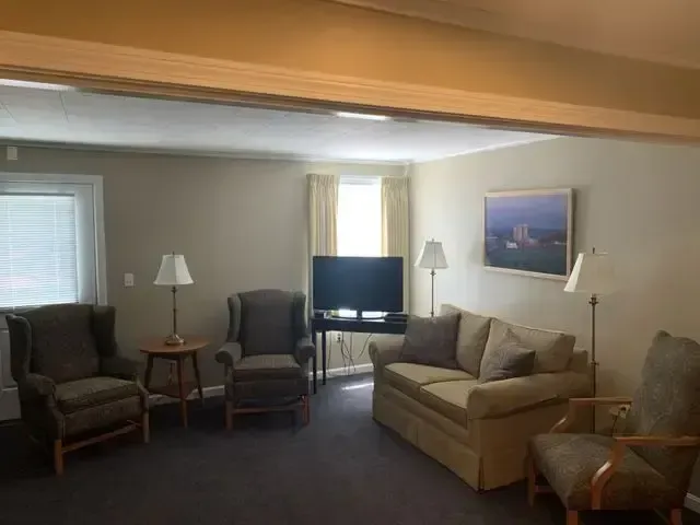 Living room with two armchairs, a sofa, lamps, and a TV near a bright window