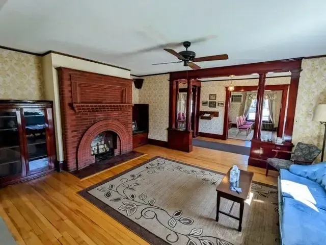 Cozy living room with brick fireplace, hardwood floors, rug, blue sofa, and French doors