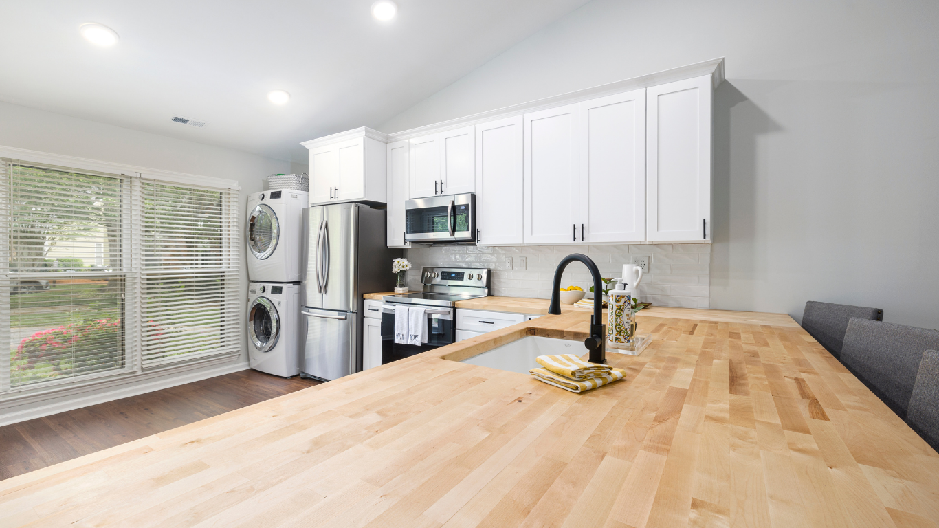 Bright kitchen with wooden countertops, white cabinets, and stainless steel appliances.