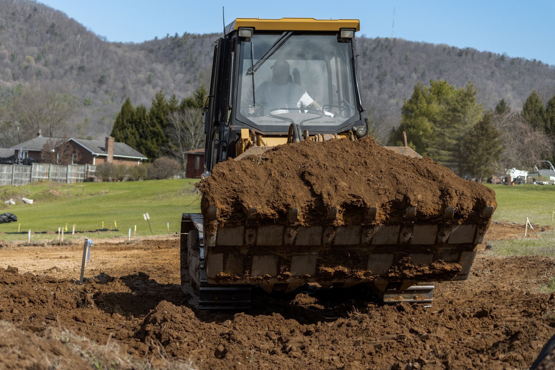 A bulldozer is moving dirt in a field with mountains in the background