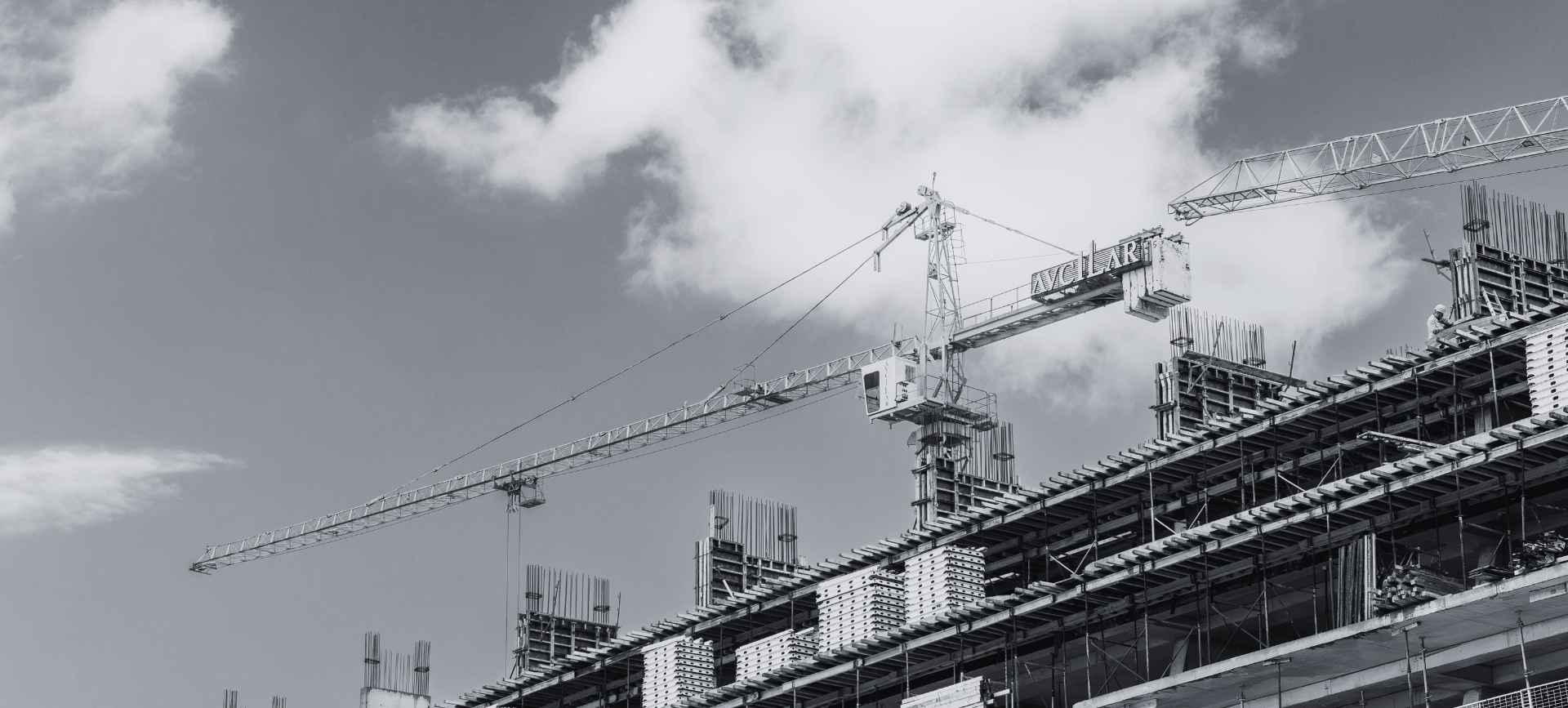 Construction cranes and scaffolding against a cloudy sky above a building site