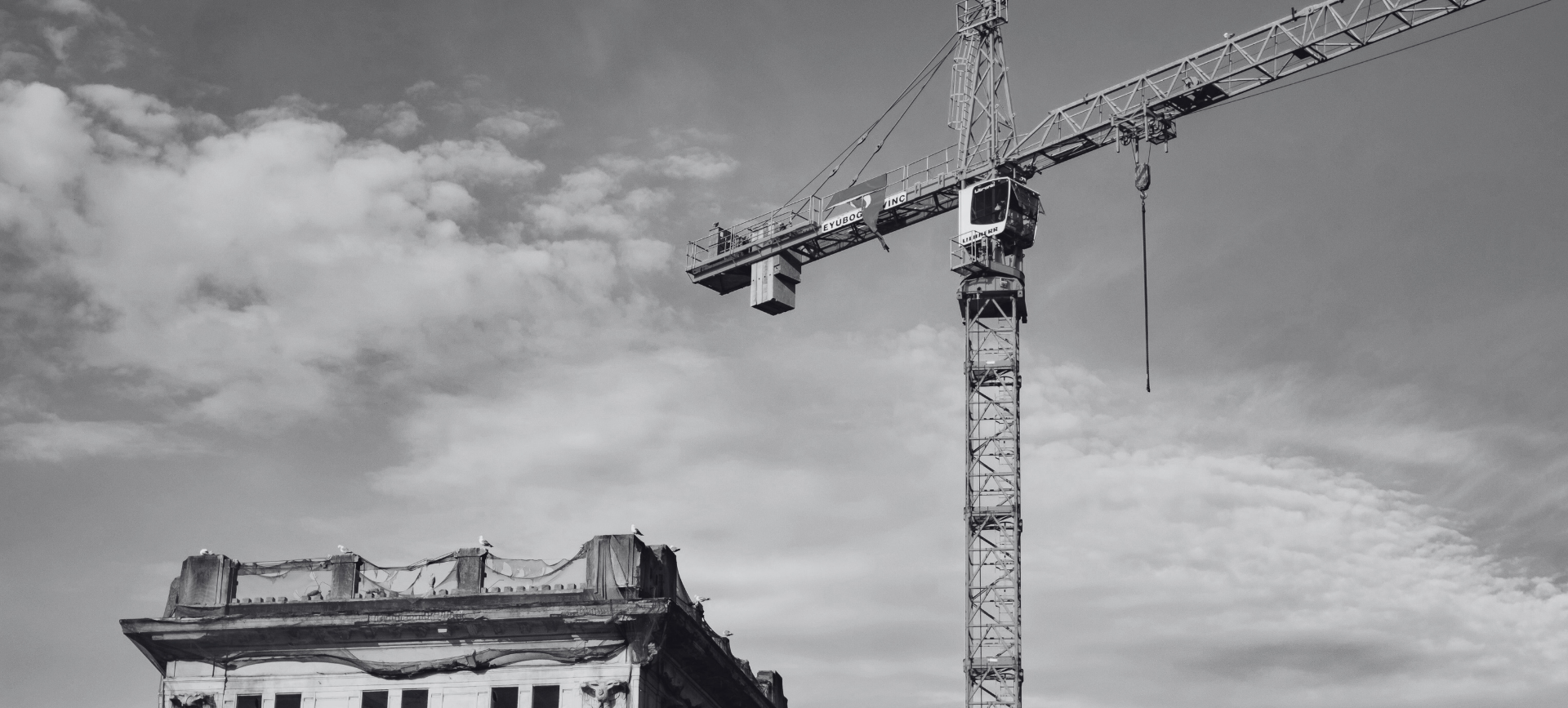 Tower crane above a damaged building under cloudy sky