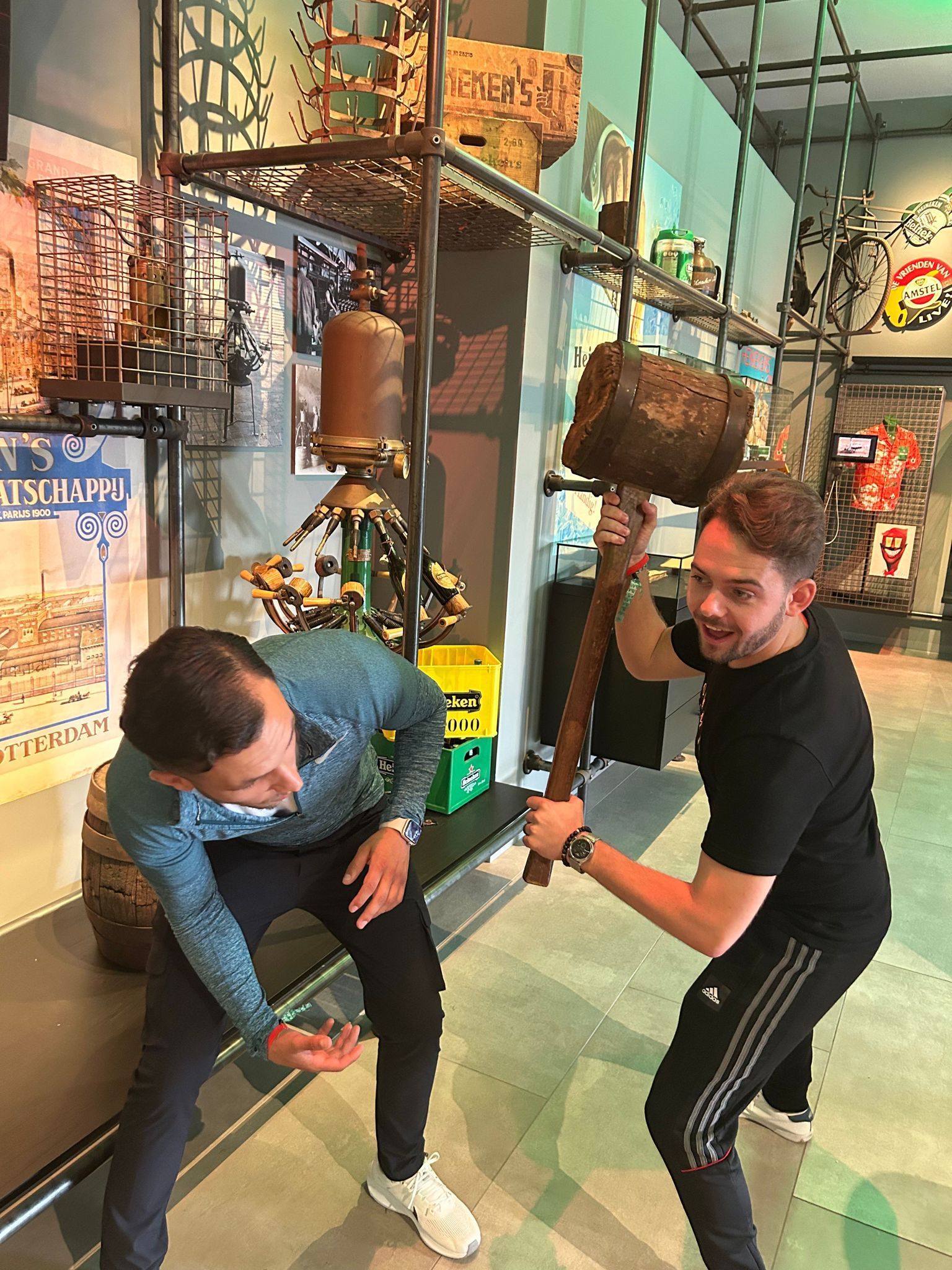 Two men in a museum exhibit try an interactive oversized hammer game.