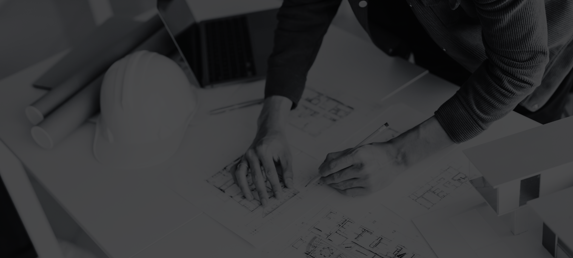 People sketching plans and diagrams on papers at a desk with a tablet nearby