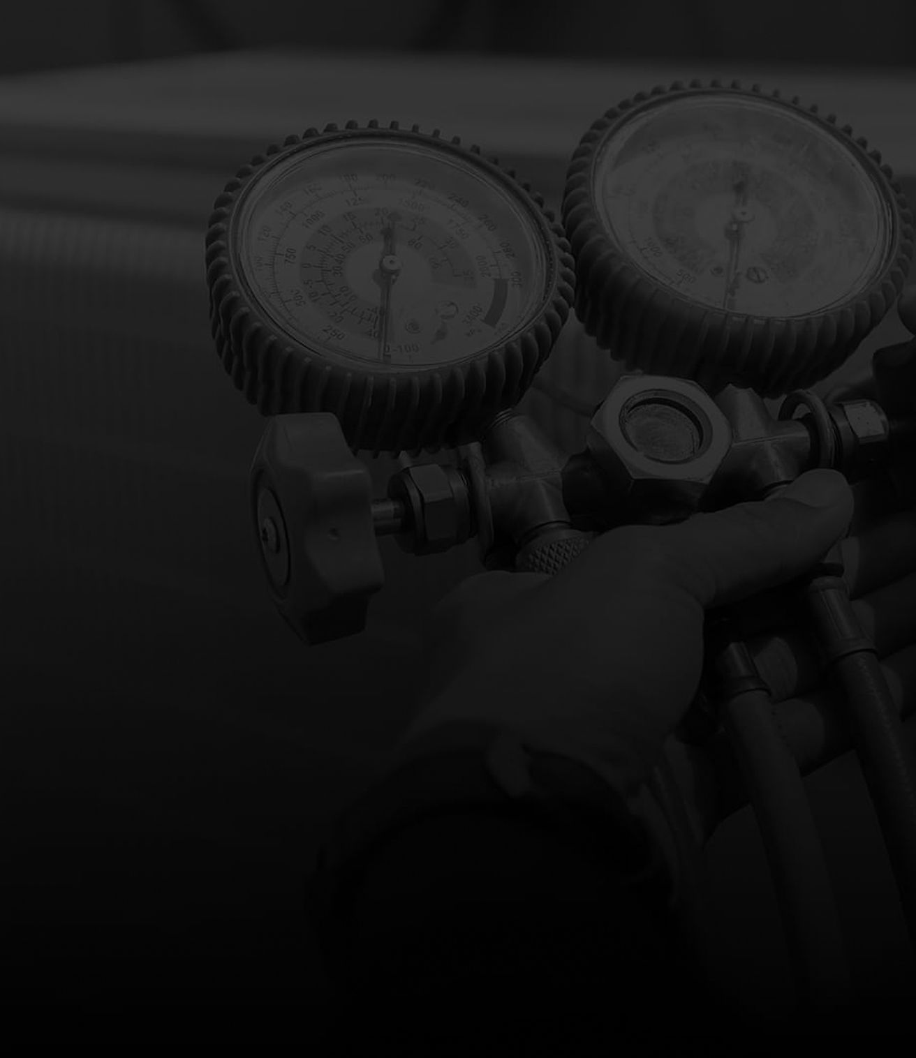 Person holding a dual gauge pressure regulator on a dark background