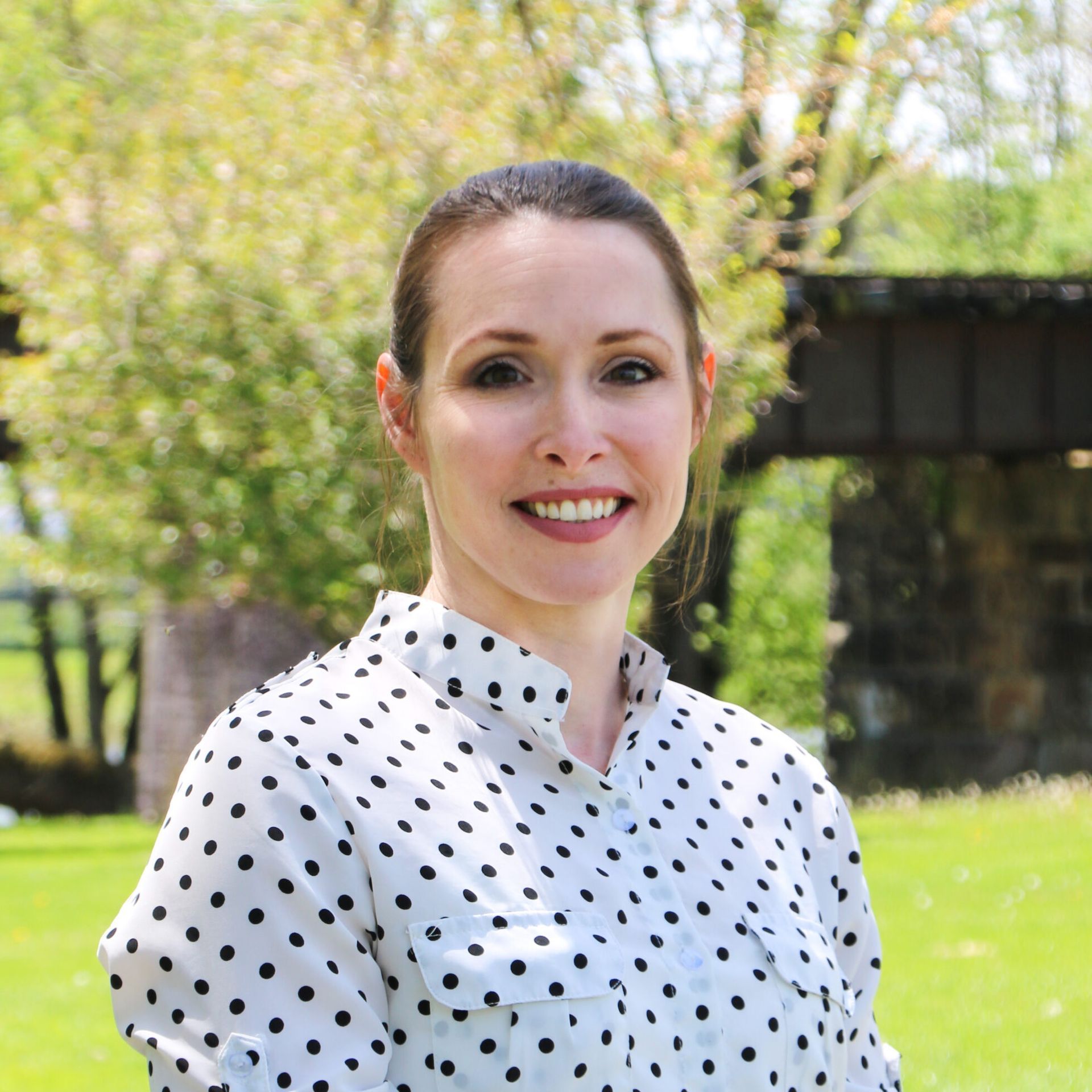 A woman in a polka dot shirt is smiling for the camera.