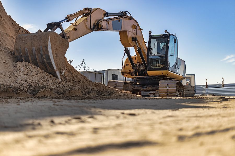 Yellow excavator loading dirt on a construction site; sunny day.