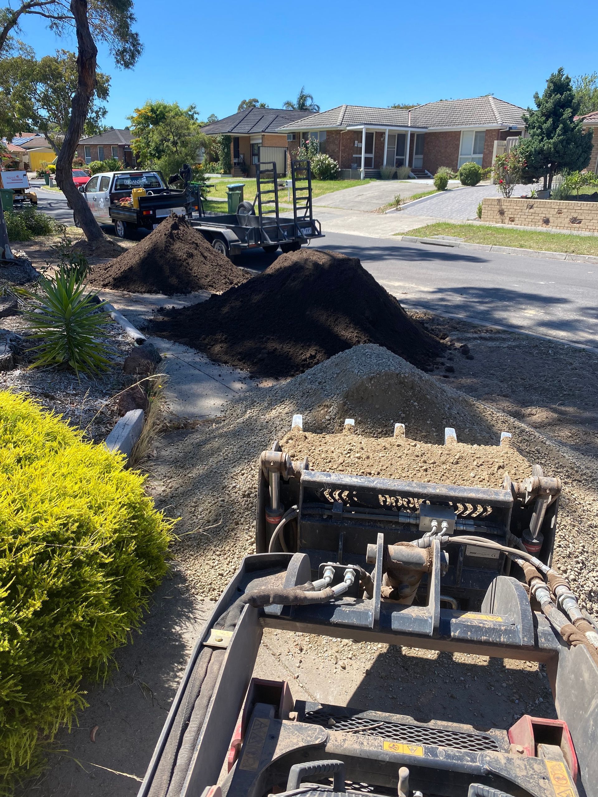 A small excavator is driving down a dirt road.