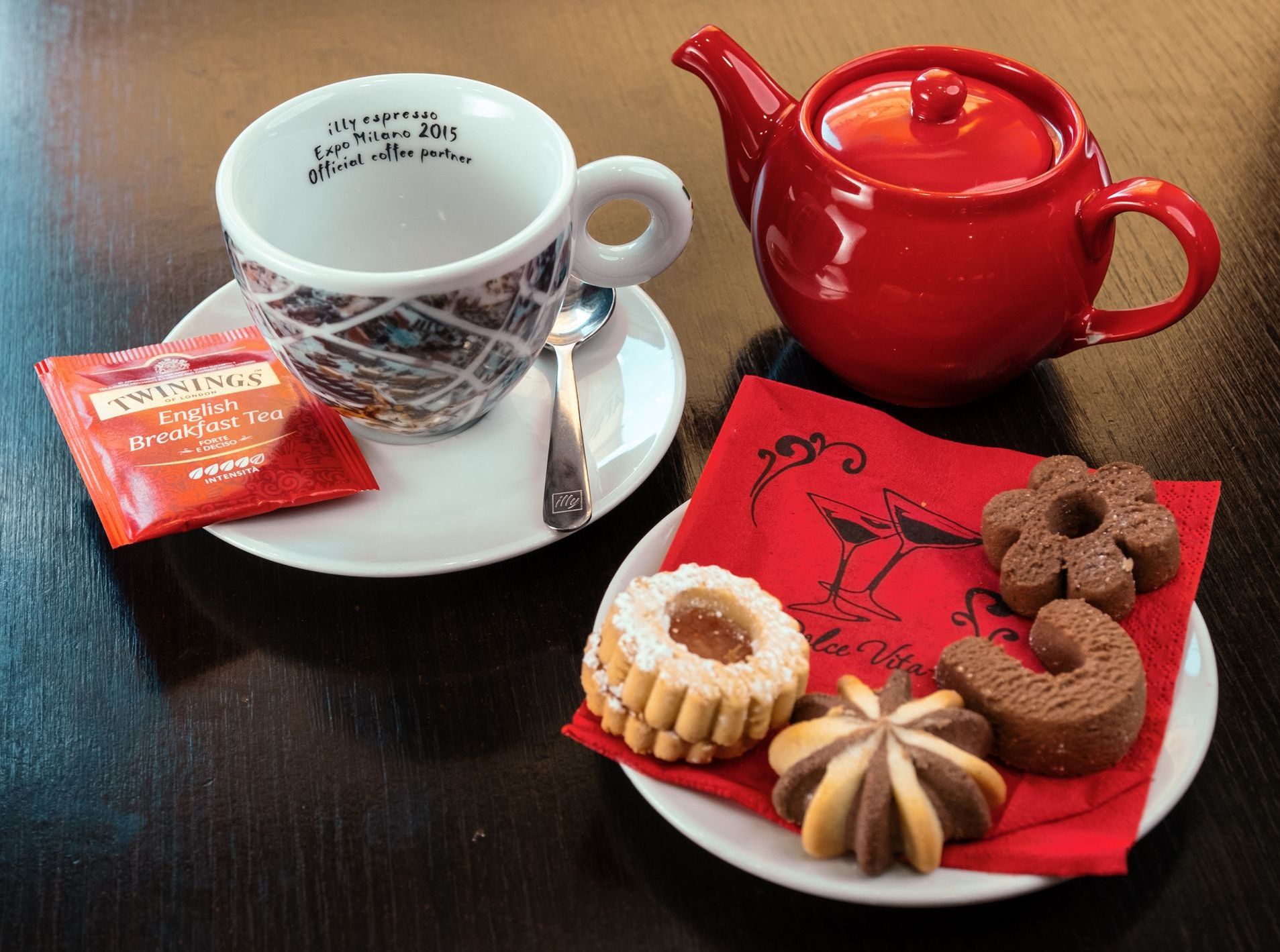 Tazza di tè con biscotti e teiera su un tavolo.