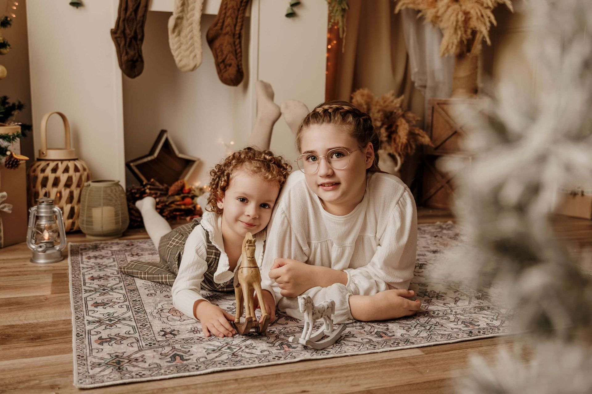 Dos niños tumbados sobre una alfombra en una acogedora sala de juegos de estilo bohemio, rodeados de decoración tejida y juguetes.