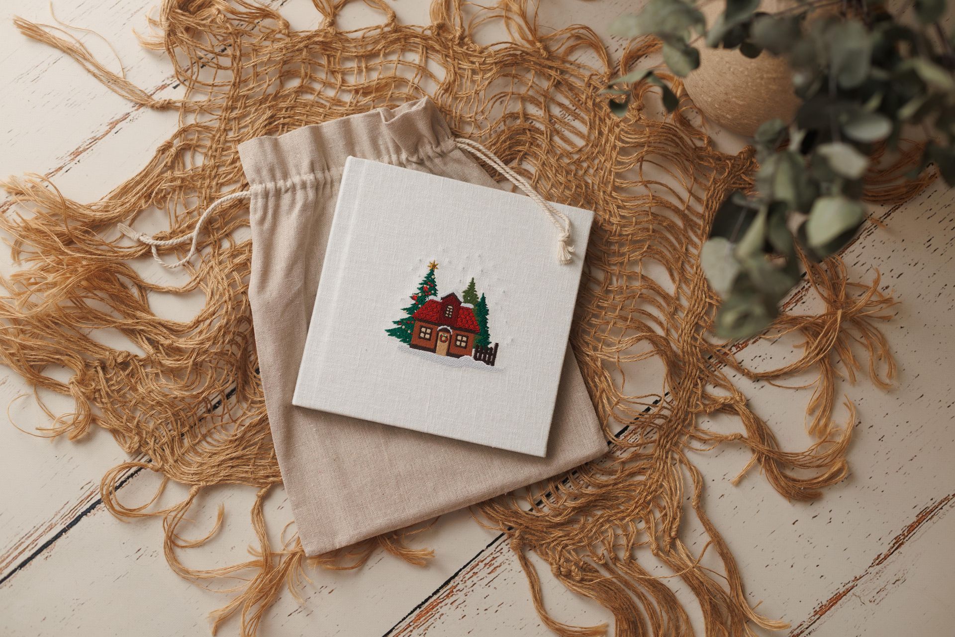 Servilleta beige doblada con una pequeña tarjeta navideña que muestra un árbol de Navidad en una decoración rústica de cordel.