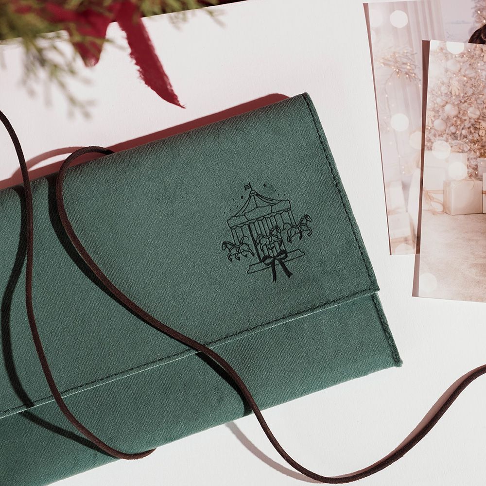 Caja de regalo verde texturizada con cinta marrón y un pequeño logotipo negro en la tapa.