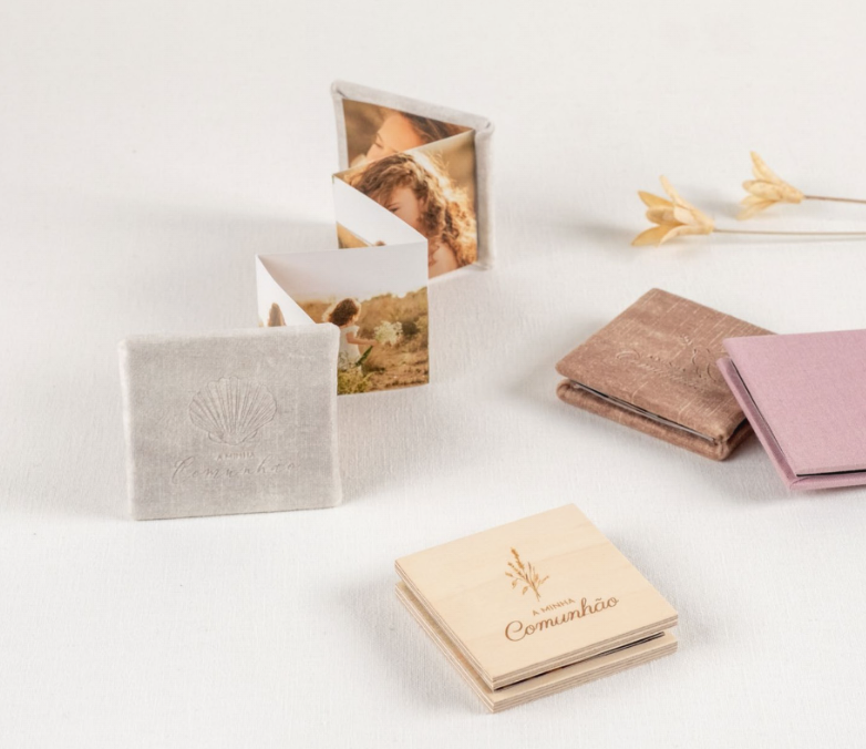 Tarjetas de folletos beige plegadas con inserciones botánicas sobre una mesa blanca, junto a tarjetas rosas y marrones.
