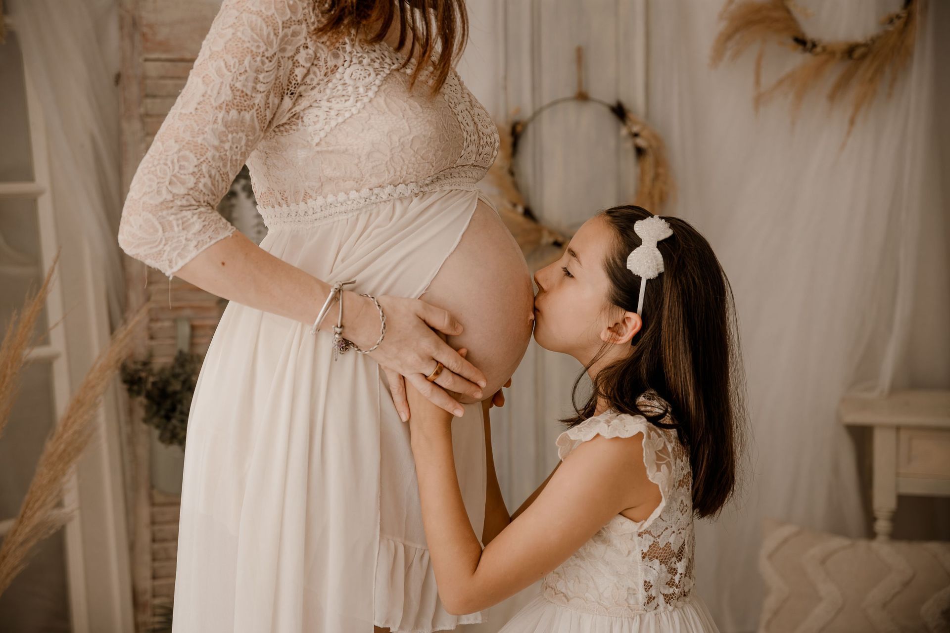 niña besando la barriga de una mujer embarazada