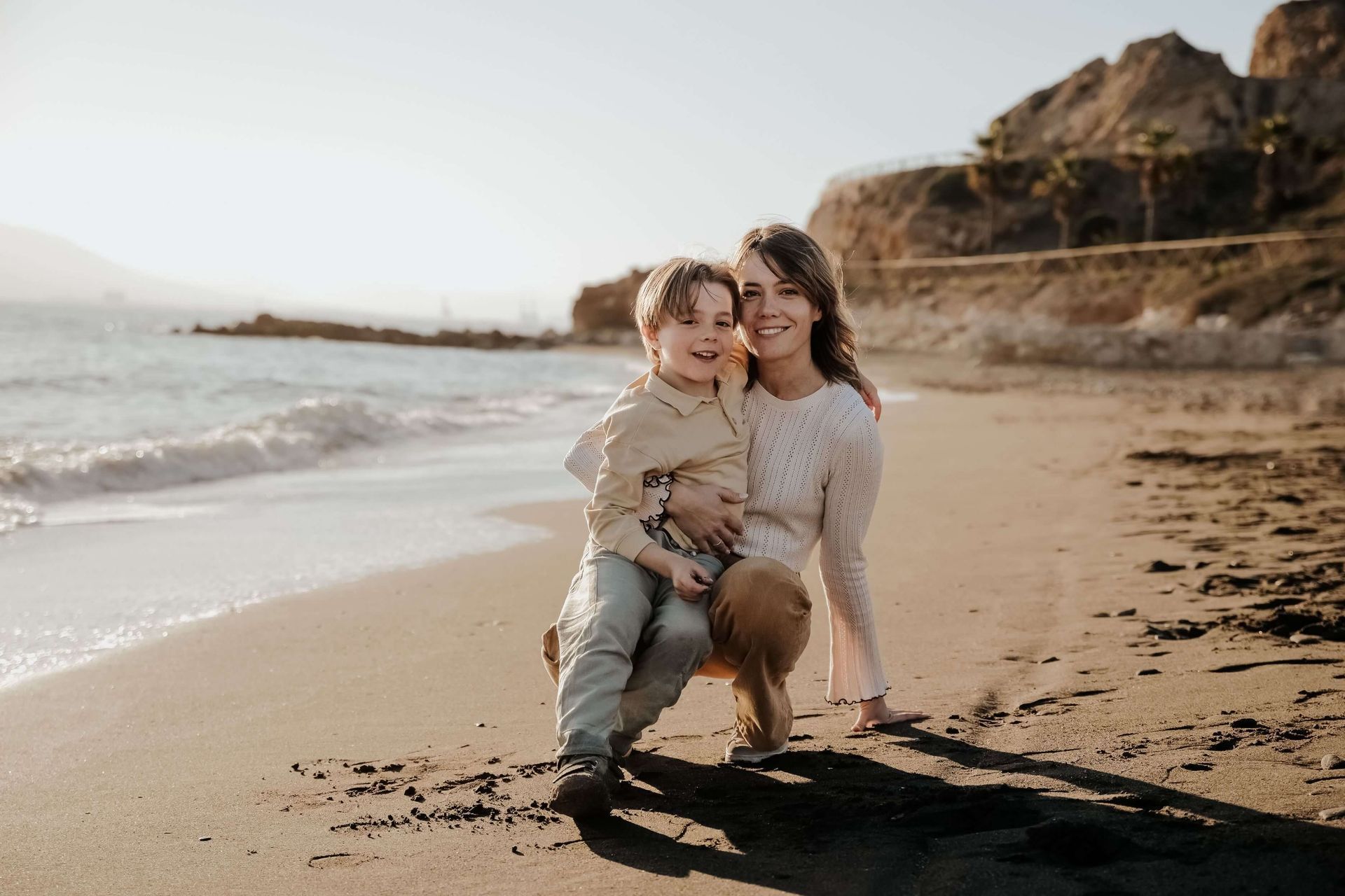 Una mujer y un niño están sentados en la playa.