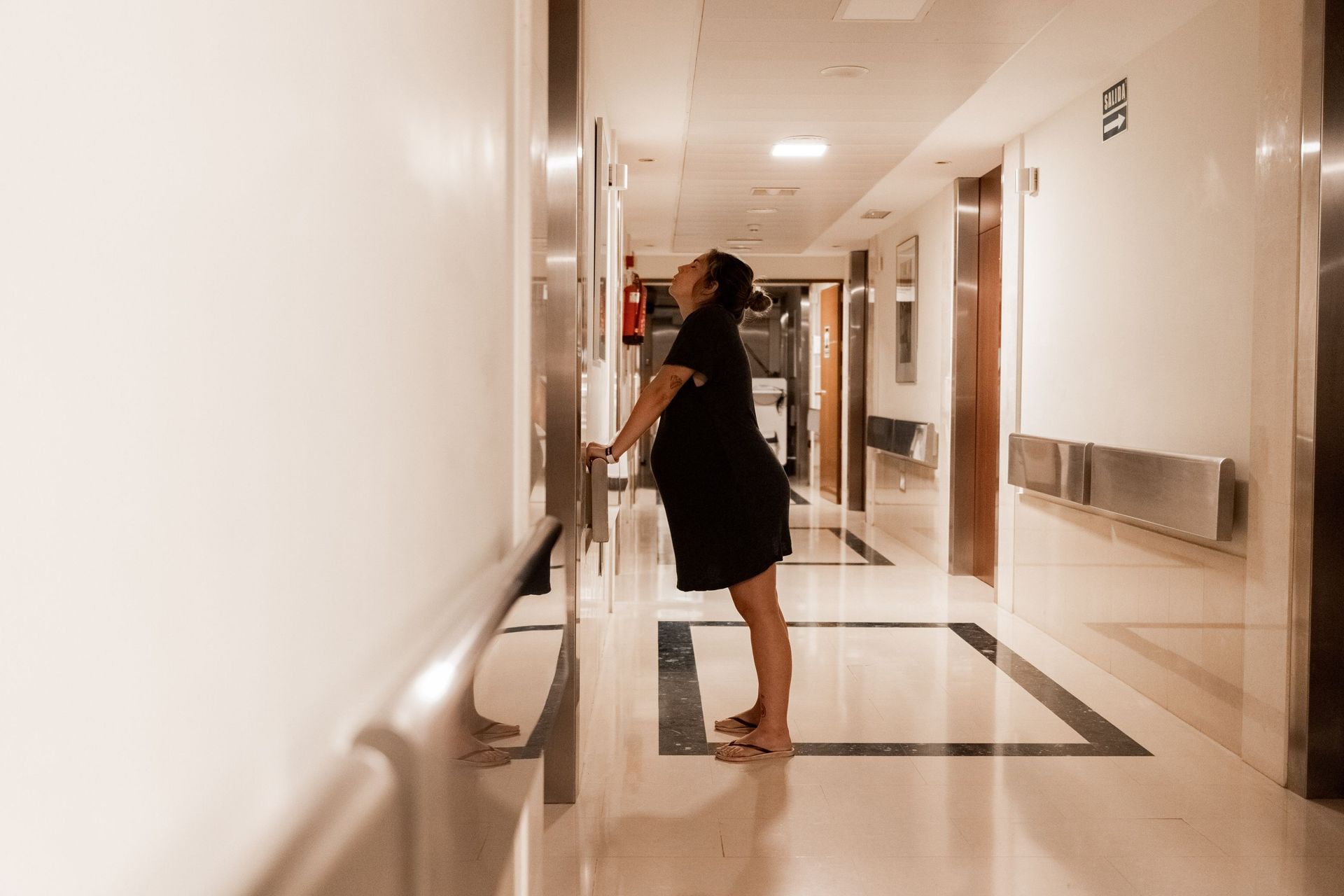 Una mujer en trabajo de parto se encuentra en el pasillo de un hospital