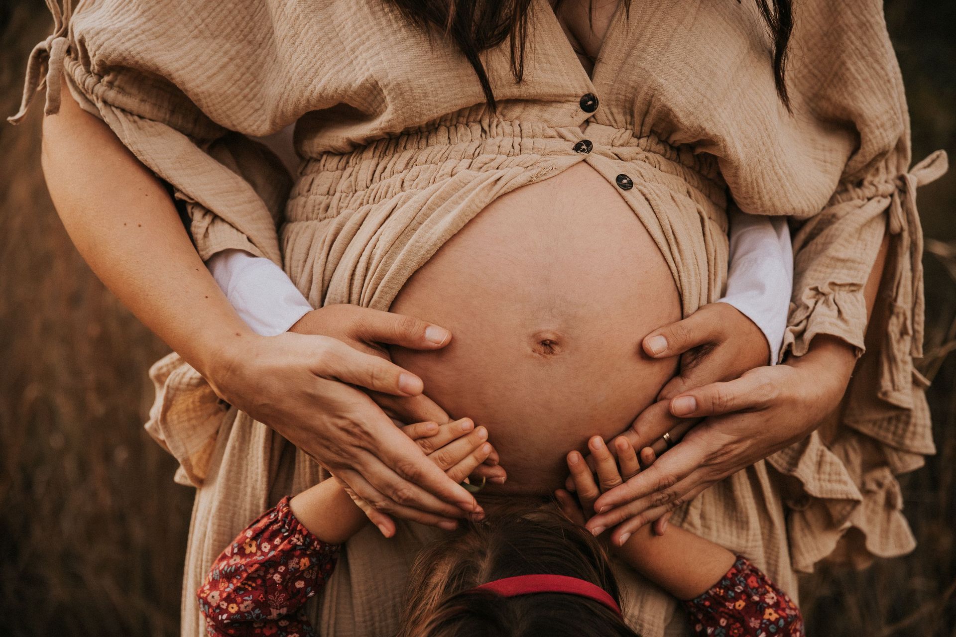 una barriga de embarazada con manos de la madre, padre e hijo.