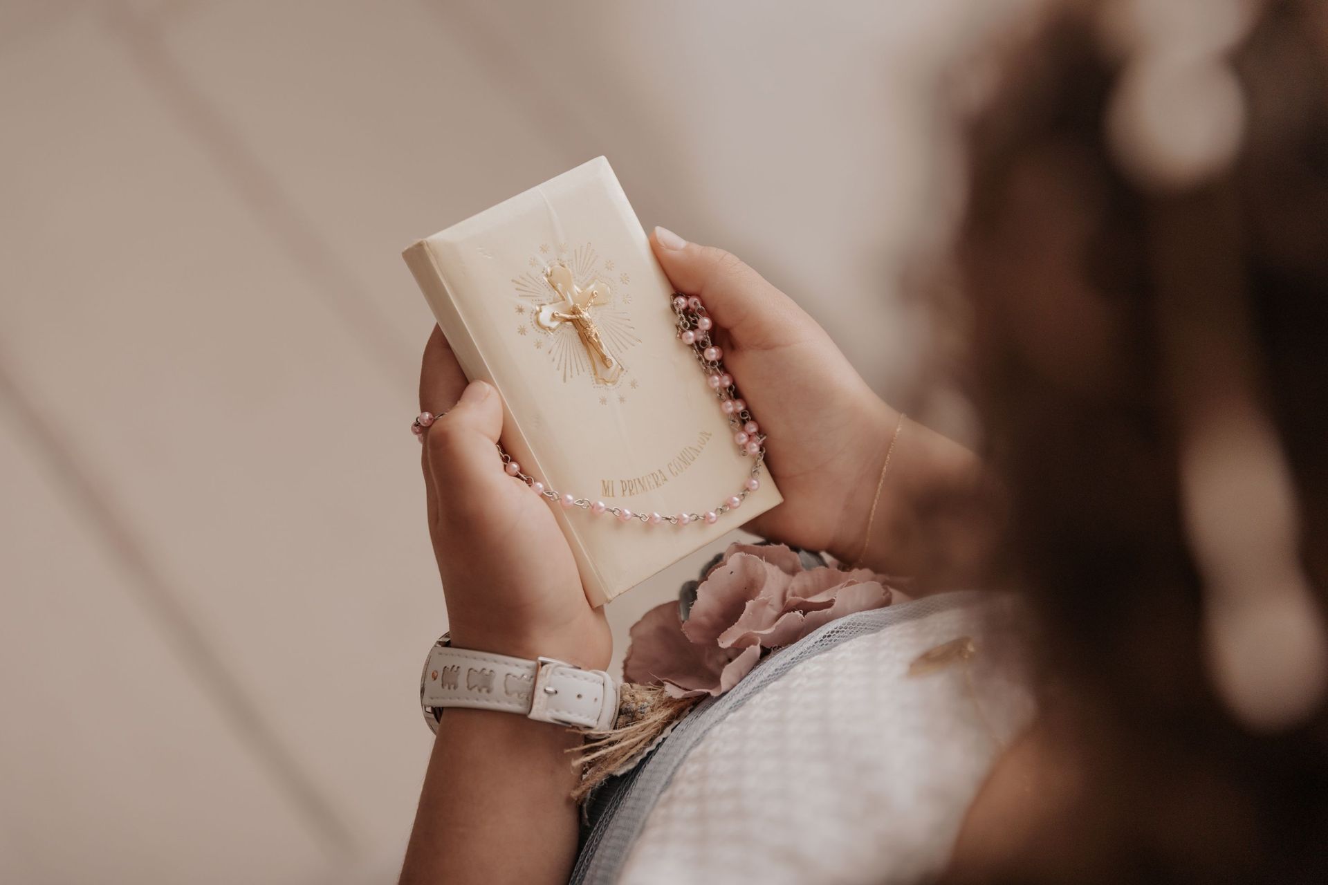 Persona sosteniendo una taza blanca con un diseño dorado, con un reloj, sobre un fondo suavemente desenfocado.