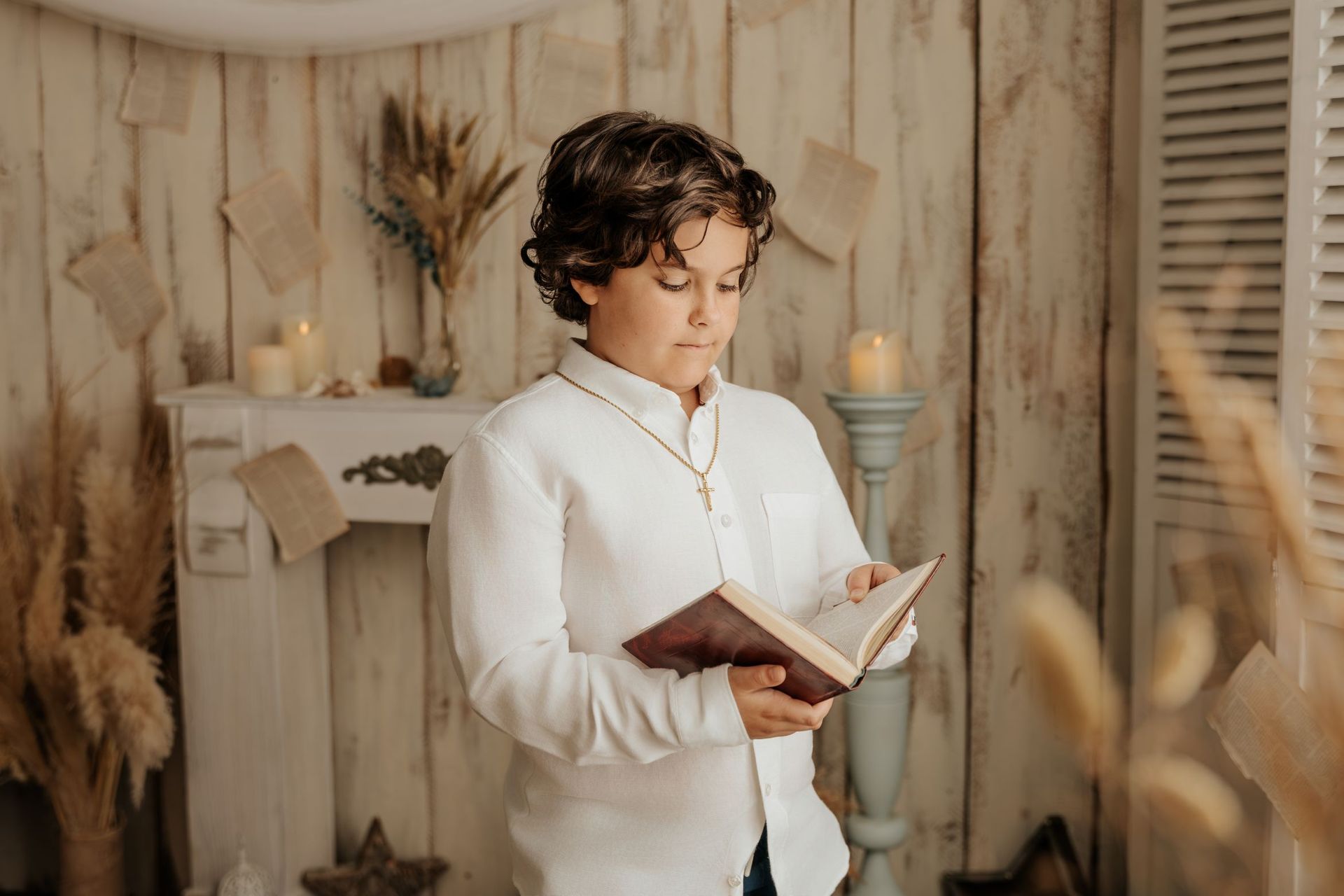 Una persona leyendo un libro en una acogedora habitación beige con flores secas y luz tenue.