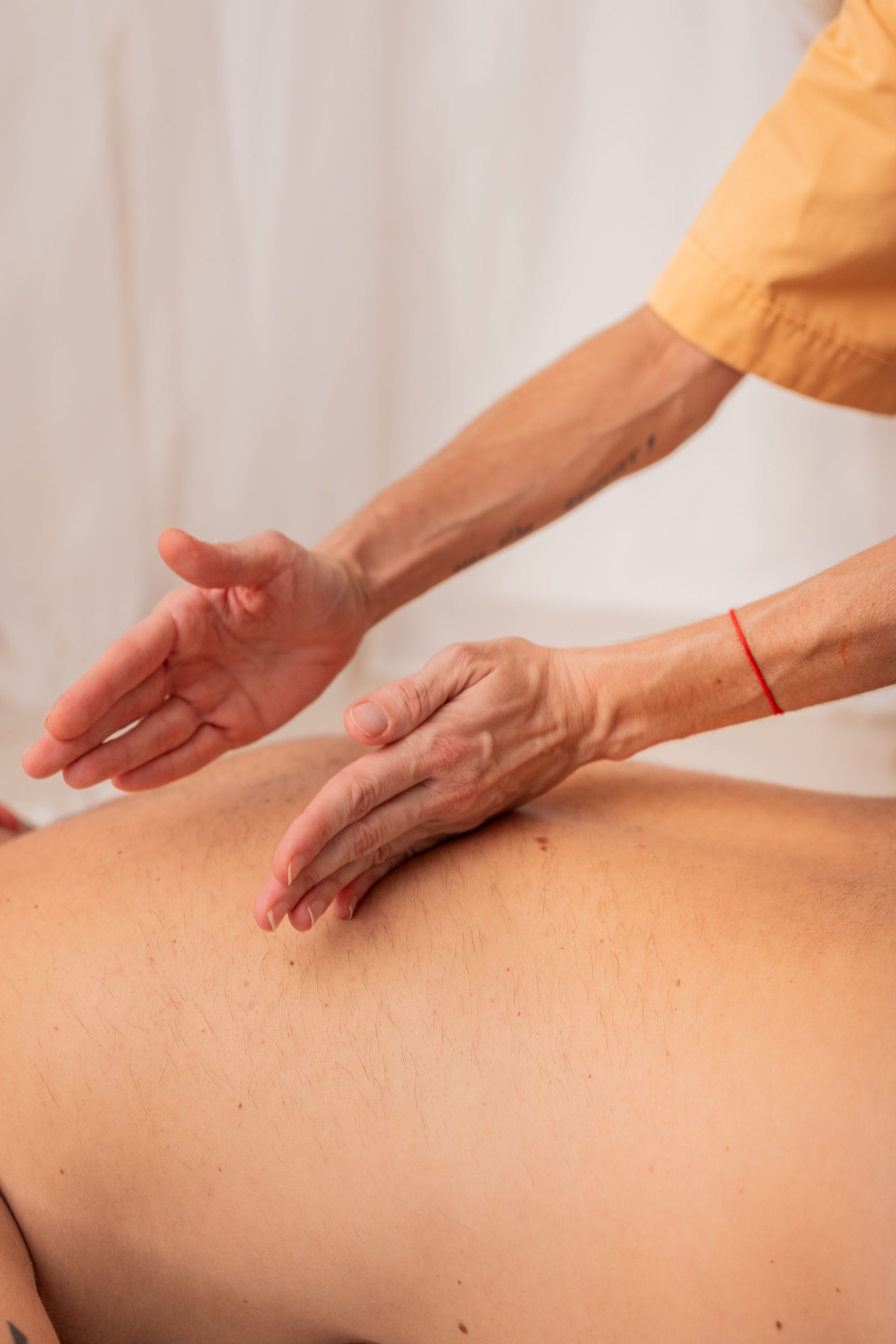 Masajista utilizando sus manos sobre la espalda de un cliente en un entorno de spa.