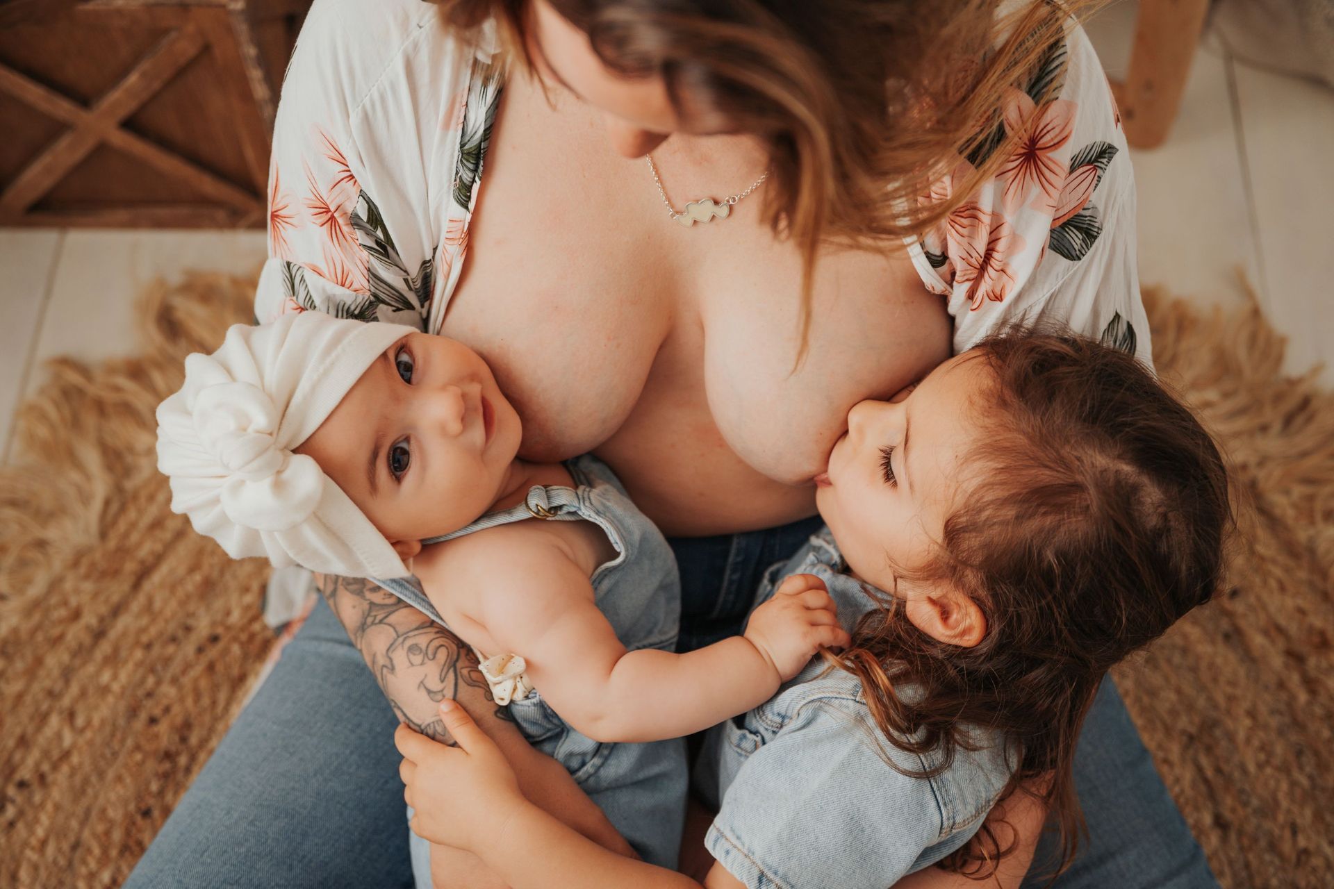 Dos bebés mamando de una mujer en un acogedor ambiente interior.